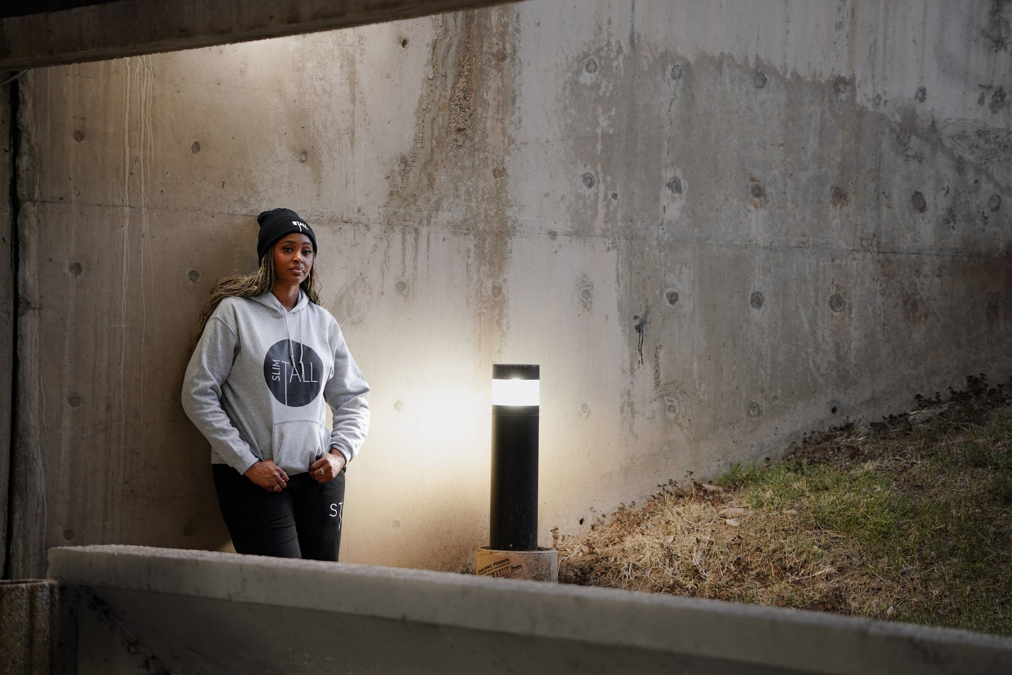 SlimTall Signature Hoodie in grey with grey circle logo and lettering, worn with black joggers and a black beanie